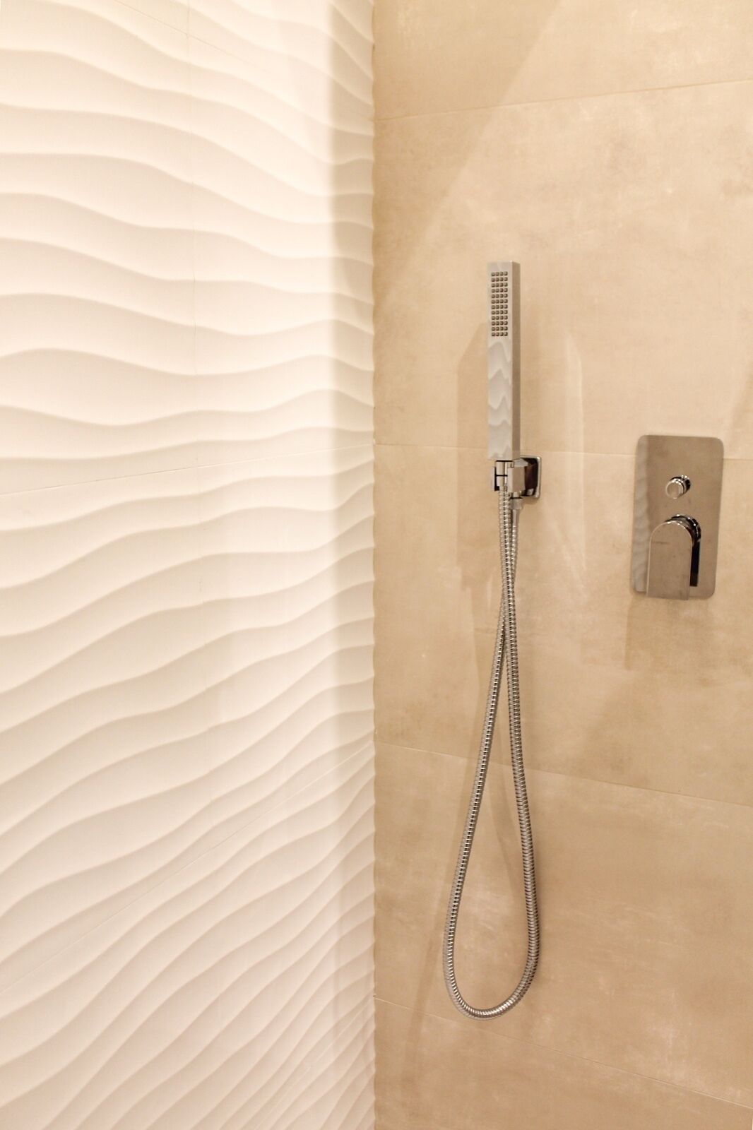 A shower with a handheld showerhead and a wall-mounted control panel.