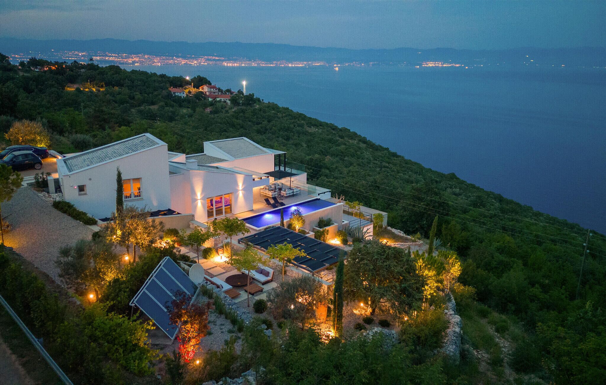 Ein modernes Haus mit Pool, Solaranlage und Meerblick.