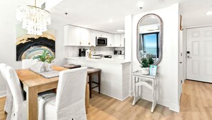 A modern kitchen with white cabinetry, a central island, and a large mirror with a decorative frame.