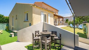 A house with a patio, a round table, and wooden chairs. - Villa 'Cap Mer 17' with Private Pool, Private Terrace and Wi-Fi (Saint-Palais-sur-Mer)
