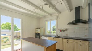 A kitchen with a wooden island, a black range hood, and a view through the sliding glass door. - Villa 'Cap Mer 17' with Private Pool, Private Terrace and Wi-Fi (Saint-Palais-sur-Mer)