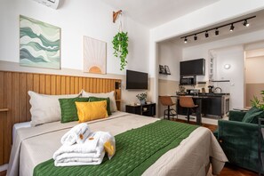 Une chambre d’hôtel équipée d’un lit, d’un bureau, d’une chaise, d’une télévision et d’une kitchenette.