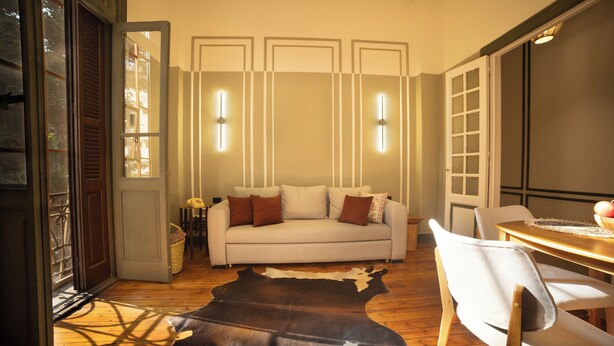 A living room with a sofa, chairs, a wooden floor, a cowhide rug, and a dining table. - Historic Boutique Apartment in Downtown Cairo (Cairo Governorate)
