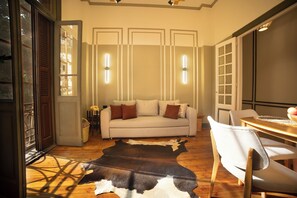 Un salon comprenant un canapé, des fauteuils, un plancher en bois, un tapis en peau de vache et une table à manger.