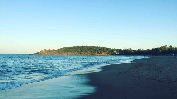 A beach with a clear sky, calm sea, and a distant hill with vegetation. - Seascape Retreat: Time to Slow Down (Agnes Water)