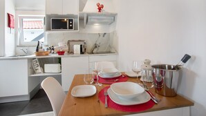 Una cocina moderna con armarios blancos, microondas, tostadora y una mesa de comedor con platos, vasos y cubiertos.