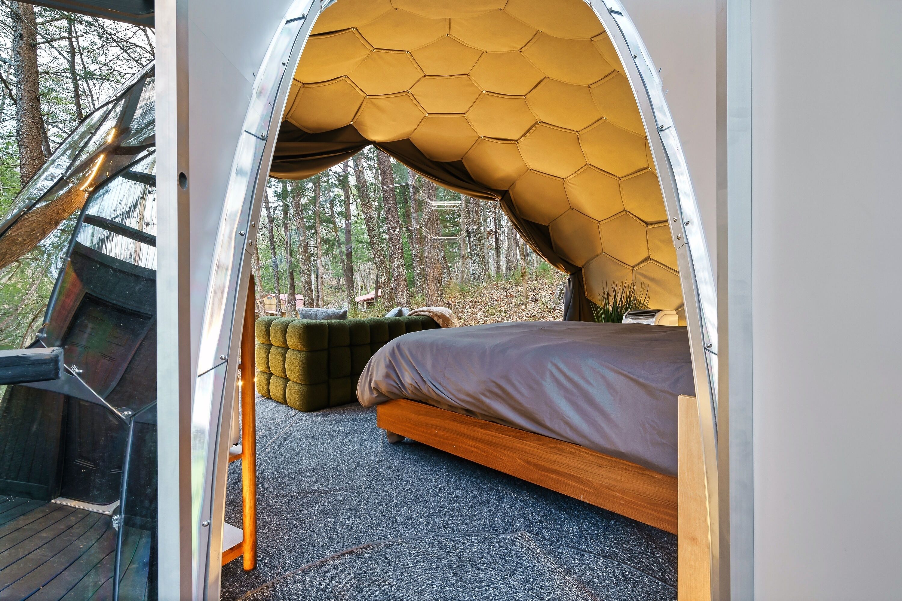 Un alojamiento tipo tienda de campaña con techo hexagonal, una cama y una zona de estar.