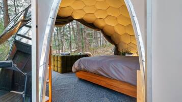 Un alojamiento tipo tienda de campaña con techo hexagonal, una cama y una zona de estar.
