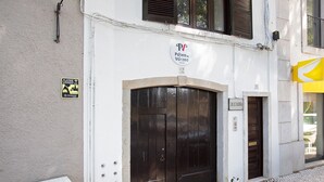 Un edificio con una puerta de madera oscura grande, un letrero que indica 'Páteo da Várzea' y un letrero de 'Solicitadora'.