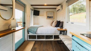 Een compacte slaapkamer met een bed, nachtkastjes, een spiegel en een raam met uitzicht.