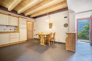 Un interno in legno con un tavolo da pranzo e sedie, una cucina con pensili e un balcone con vista.