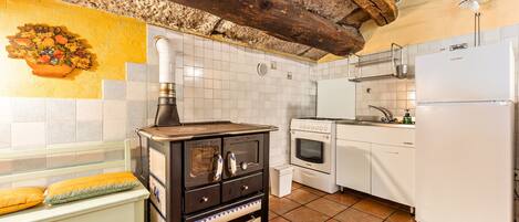 Een koelkast, een oven, een kookplaat, kookgerei, borden en bestek