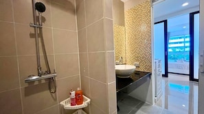 Une salle de bain moderne équipée d’une douche, d’un lavabo et d’un petit panier de rangement.
