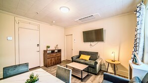 A modern living room with a sofa, coffee table, and a TV mounted on the wall. - Renovated 1-Bedroom Apartment in Beautiful Downtown Falmouth Located on Main St (Falmouth)