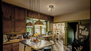 Una cocina con armarios de madera, una isla central, lámparas colgantes y suelo de cuadros.