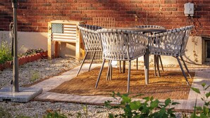 Un patio con una mesa, sillas, una sombrilla y un muro de ladrillo.