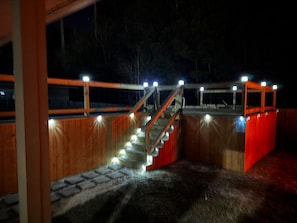A wooden staircase with railings and lights, leading to a covered area with a red wall and a sign. - Close to Chappapeela Open Floor plan with Pool (Ponchatoula)