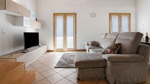 A living room with a sofa, TV, wooden cabinets, and a window with blinds. - Apartment 'Casa Zia Dani' with Mountain View, Private Terrace and Wi-Fi (Piantedo)