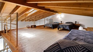 A loft bedroom with a wooden ceiling, two beds, a ladder, and a radiator. - Apartment 'Casa Zia Dani' with Mountain View, Private Terrace and Wi-Fi (Piantedo)