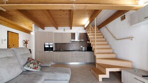 A modern interior with a sofa, kitchen, and wooden staircase. - Apartment 'Casa Zia Dani' with Mountain View, Private Terrace and Wi-Fi (Piantedo)