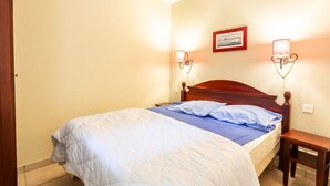 A neatly made bed with a blue and white duvet, a wooden headboard, and two wall-mounted reading lamps. - Close to the lake, beautiful apartment residence with swimming pool (BISCARROSSE)