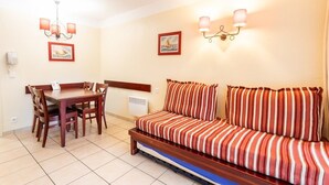 A compact living space with a dining table, chairs, a sofa, and a chandelier. - Close to the lake, beautiful apartment residence with swimming pool (BISCARROSSE)