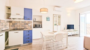 A modern kitchen with a microwave, toaster, and a dining area with chairs and a table. - Apartment 'Bilo Terrazza Rio Elba' with Mountain View, Balcony and Air Conditioning (Rio Nell'elba)