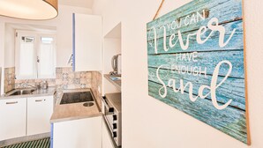 A kitchen with a sink, stove, and a wall-mounted sign. - Apartment 'Bilo Terrazza Rio Elba' with Mountain View, Balcony and Air Conditioning (Rio Nell'elba)