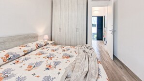A bedroom with a bed, a nightstand, a lamp, a wardrobe, and an air conditioning unit. - Apartment 'Bilo Terrazza Rio Elba' with Mountain View, Balcony and Air Conditioning (Rio Nell'elba)