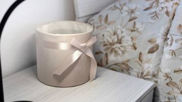 A beige candle holder with a ribbon on a bedside table.