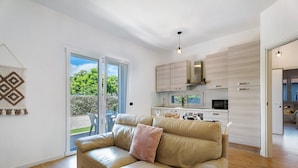 Ein modernes Wohnzimmer mit einer Ledersofa, einem Essbereich mit hellen Holzschränken und einer Glastür zum Balkon.