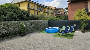 Ein Wohngebiet mit Schwimmbad, Gartenmöbeln und einer Hecke.