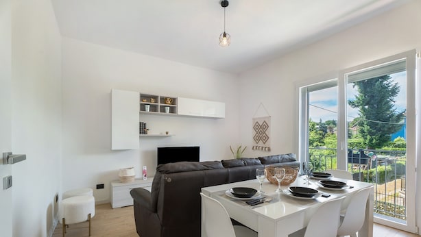 Ein modernes Wohnzimmer mit Essbereich, einer Couch, einem Fernseher und einem Balkon mit Blick.