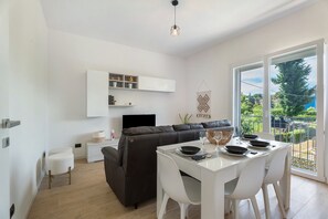 Un espace de vie moderne comprenant un coin repas, un canapé, un téléviseur et un balcon avec vue.