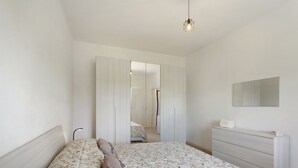 Ein Schlafzimmer mit einem Bett, einem Schminktisch, einem Spiegel und einem Kleiderschrank.