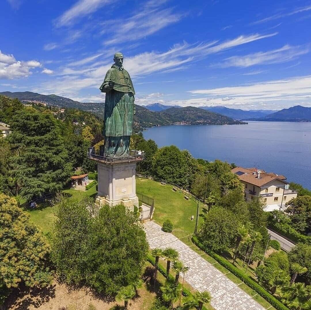 Una estatua sobre un pedestal, con vista despejada a un lago y montañas al fondo.