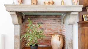 A fireplace with a brick wall, a potted plant, and a large vase.
