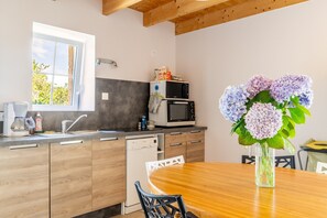 A modern kitchen with wooden cabinets, a built-in dishwasher, a microwave, and a dining area with a wooden table and chairs.