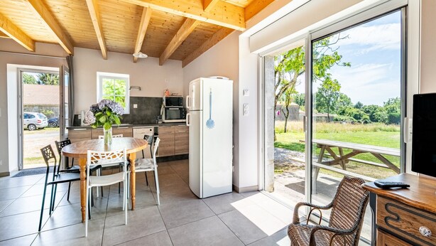 Una cocina moderna con comedor, refrigerador y vistas al exterior.