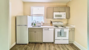 A compact kitchen with a refrigerator, dishwasher, microwave, stove, and sink.