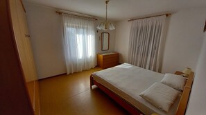 Un dormitorio con cama, mesita de noche, cómoda, espejo y candelabro.