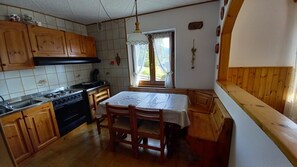 Una cocina con armarios de madera, estufa y una mesa de comedor con sillas.