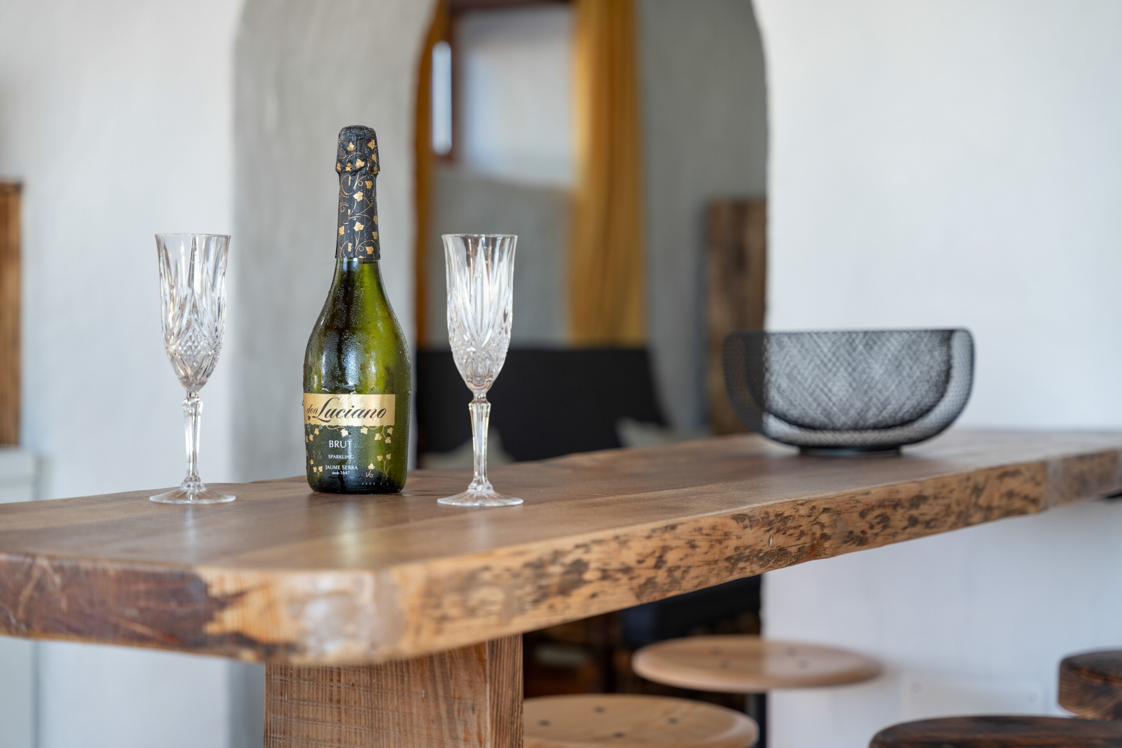 A wooden bar counter with a bottle of wine and two glasses on it.