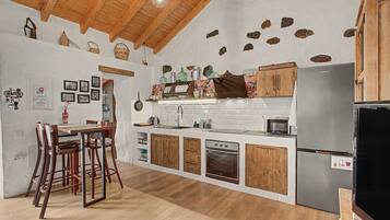 A kitchen with wooden cabinets, a stainless steel refrigerator, and a dining area with a table and chairs.