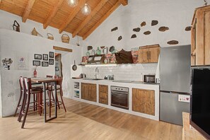 Eine Küche mit Holzausstattung, einem Edelstahlkühlschrank und einem Essbereich mit Tisch und Stühlen.