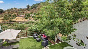 Un jardin avec une piscine, du mobilier d’extérieur et une vue sur le paysage environnant.