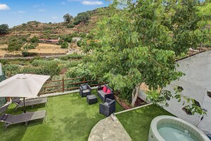Un patio trasero con piscina, mobiliario exterior y vistas del paisaje circundante.