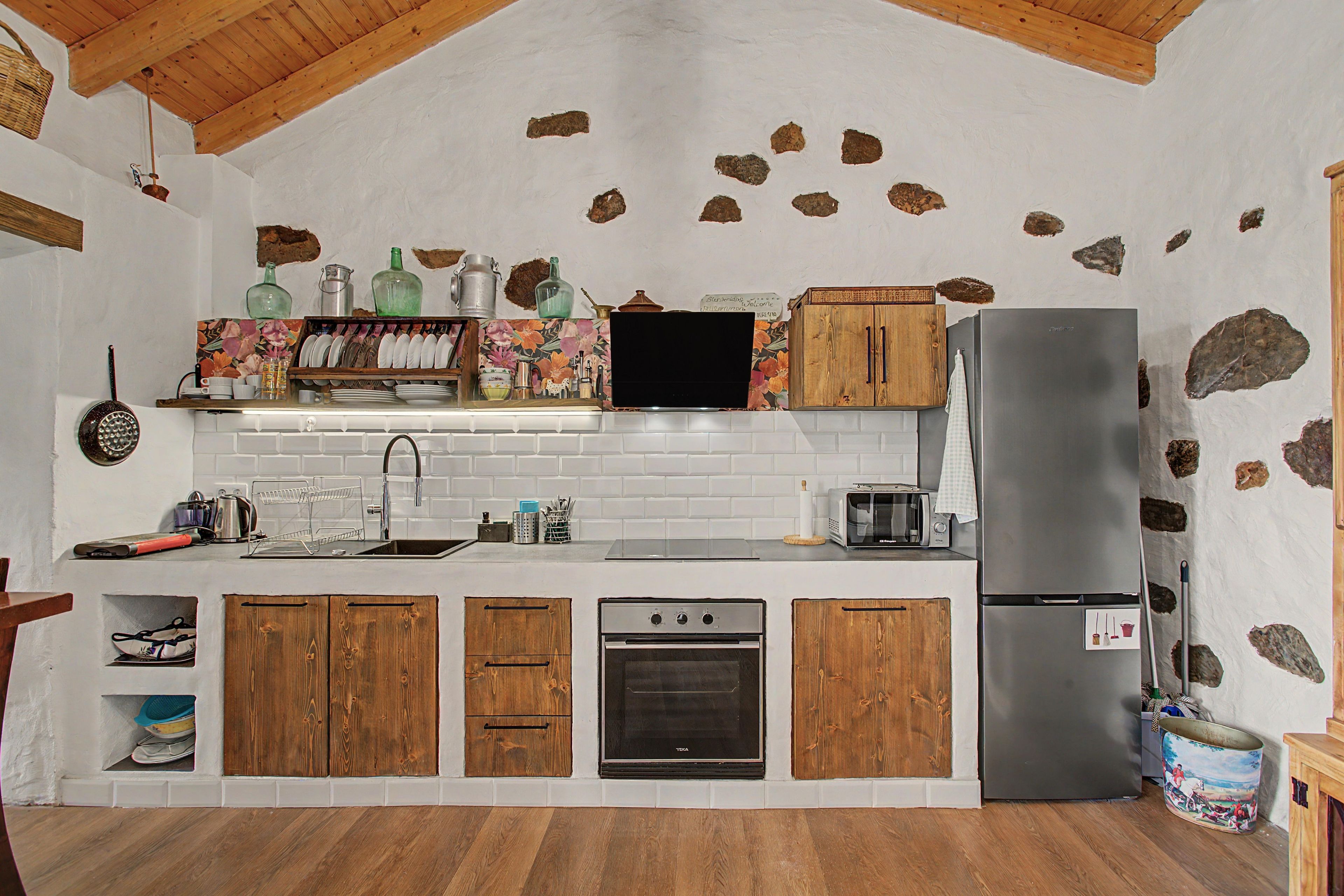 A kitchen with wooden cabinets, a stainless steel refrigerator, a built-in oven, and a microwave.