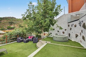 Eine Terrasse mit Gartenmöbeln, einem Whirlpool und Blick auf die umliegende Landschaft.