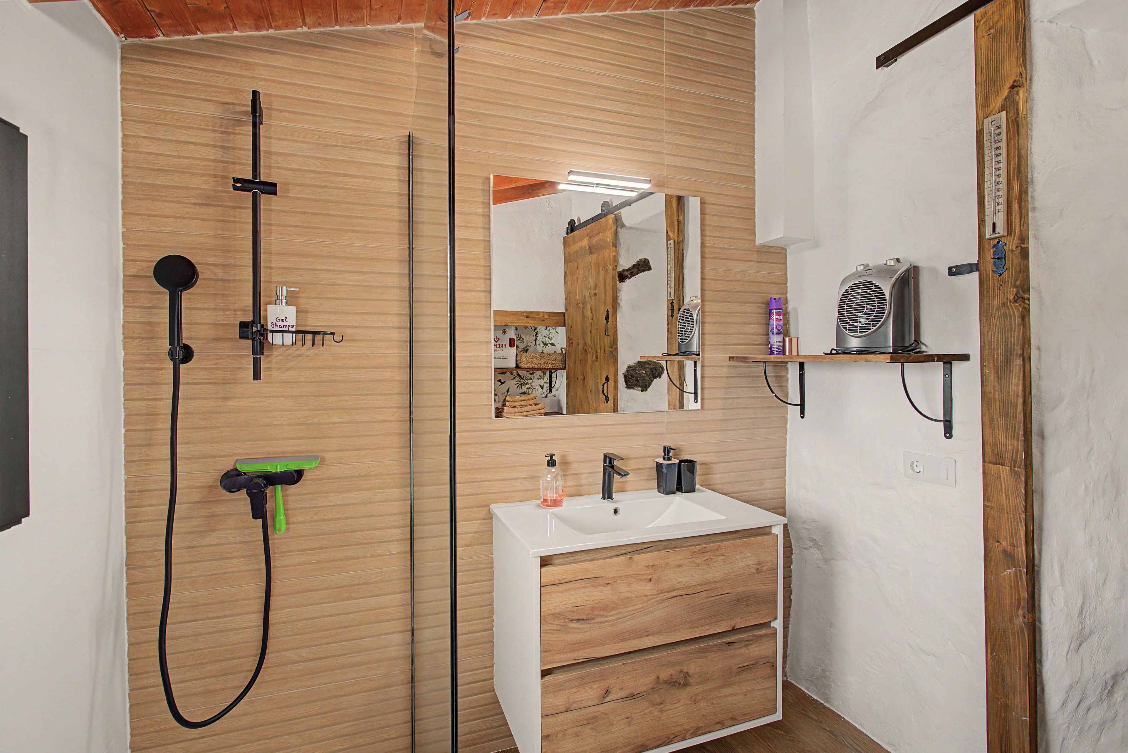 Een moderne badkamer met een houten wastafelmeubel, een grote spiegel en een douchehoek.
